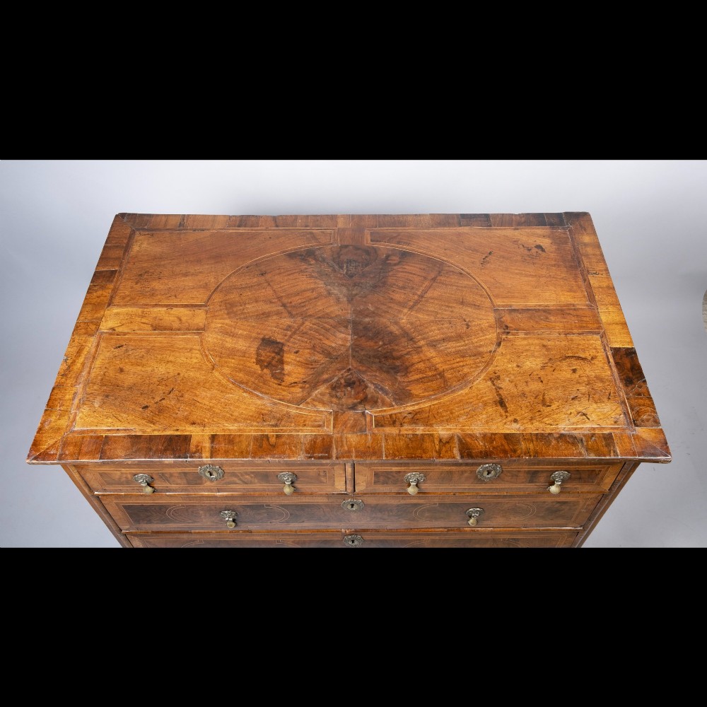 An early 18th-century inlaid walnut chest of drawers featuring two short over three long drawers, brass drop handles, and bracket feet. View IV