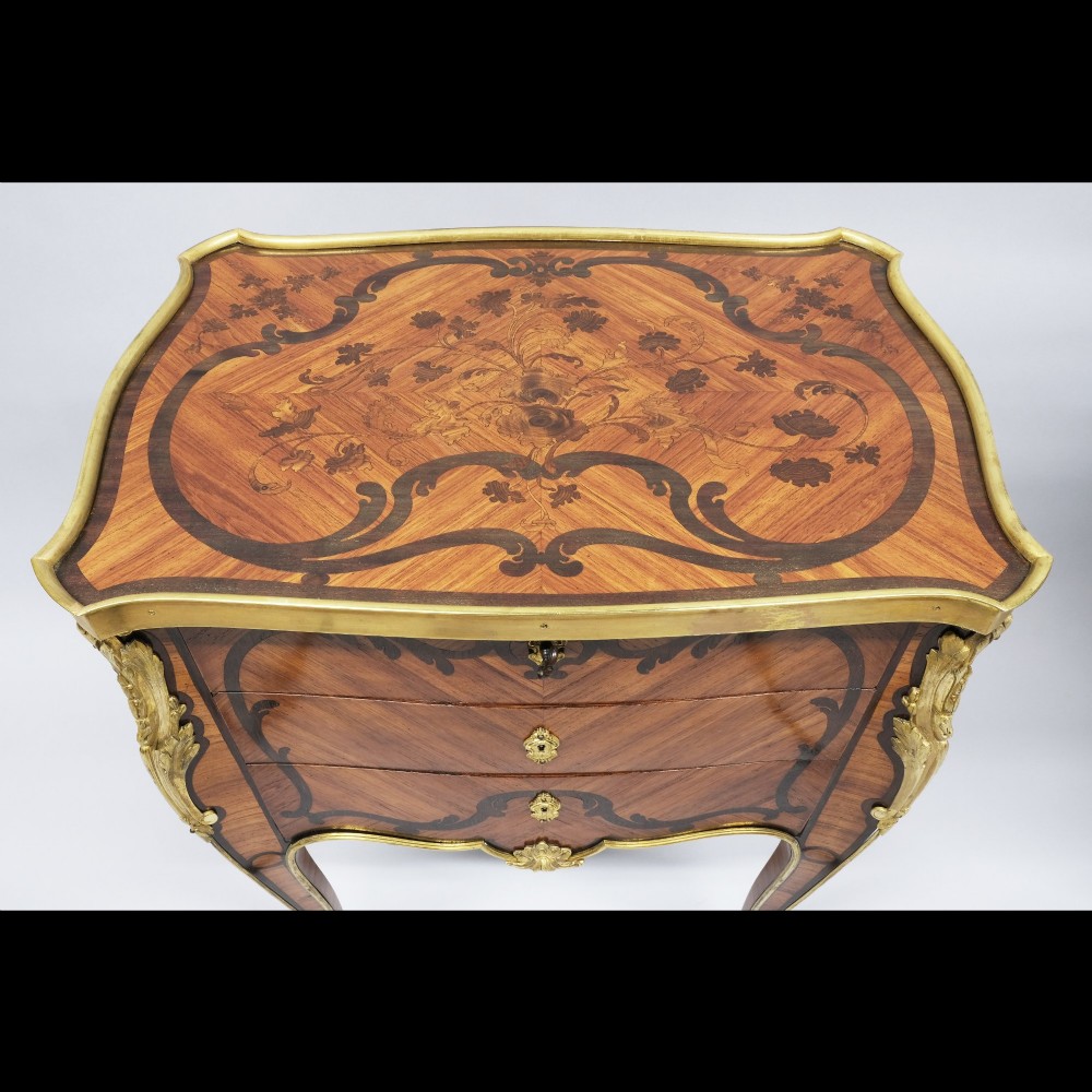 A pair of French Louis XV style inlaid timber commodes featuring serpentine fronts, marquetry veneering, cabriole legs, and chased gilt-bronze mounts. View II