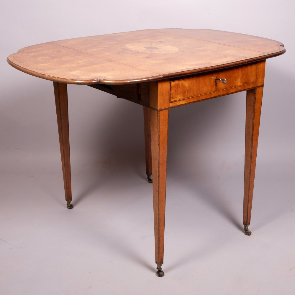 An 18th-century Georgian satinwood Pembroke table featuring extended drop leaves, a central fan marquetry inlay, crossbanded borders, a frieze drawer with key, and tapered legs ending in brass castors. View III