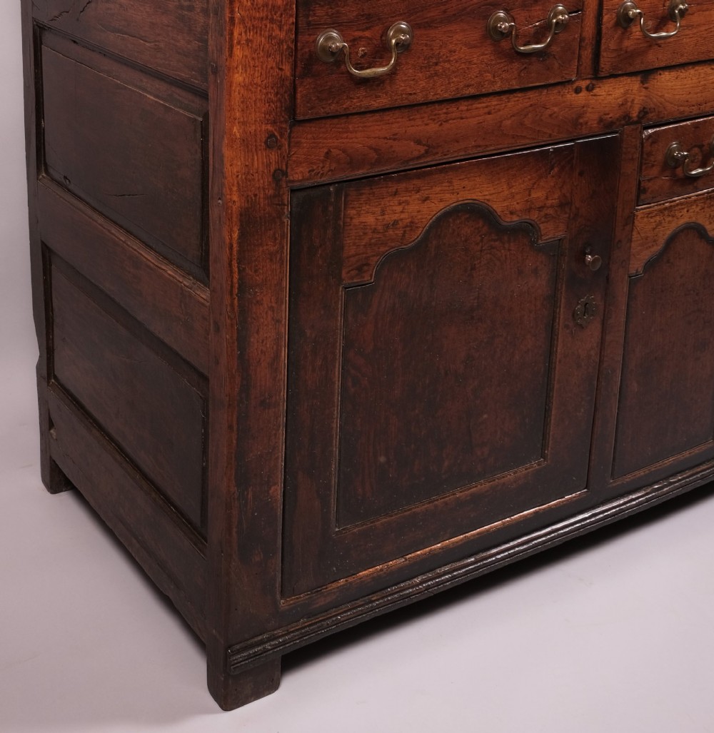 Mid 18th-century Welsh oak dresser with an open plate rack, scalloped top frieze, small spice drawers, and a base containing drawers and panelled cupboards. View II