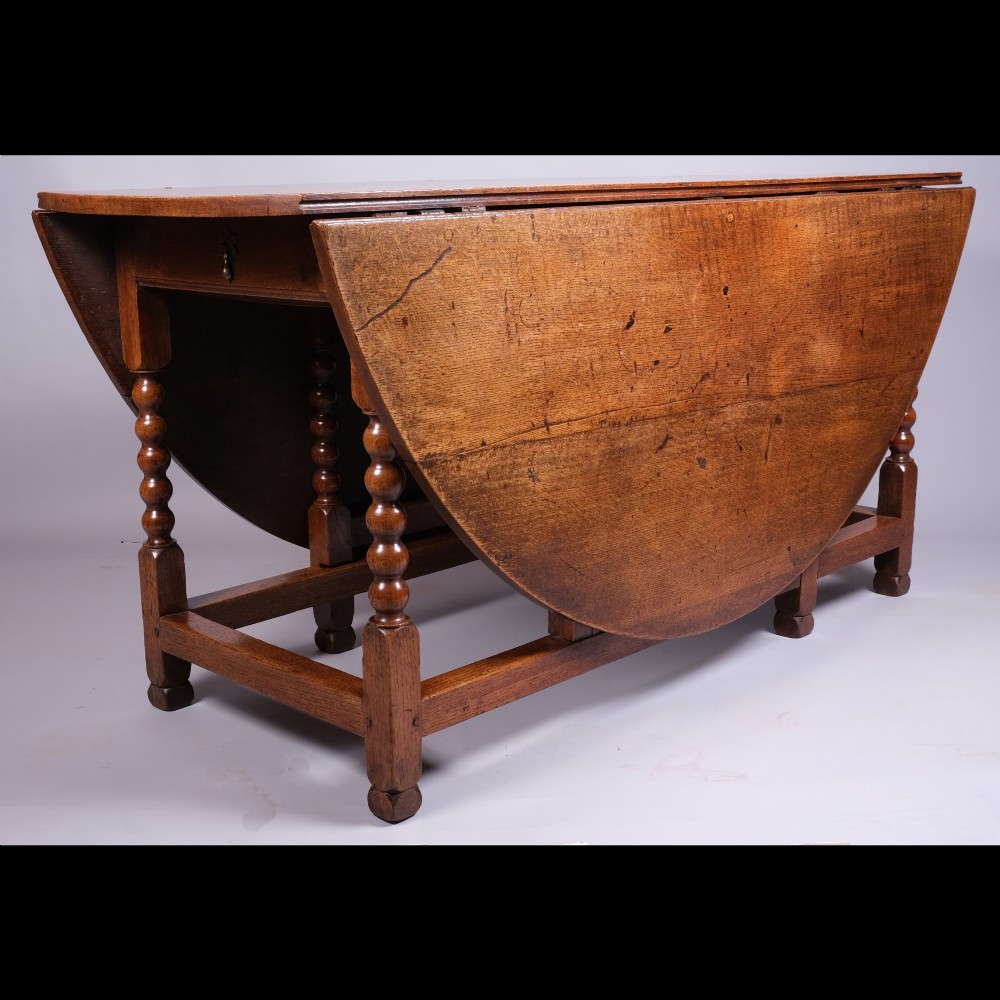 A 17th-century oak gateleg table featuring two drop leaves, bobbin-turned legs, and lower perimeter stretchers.