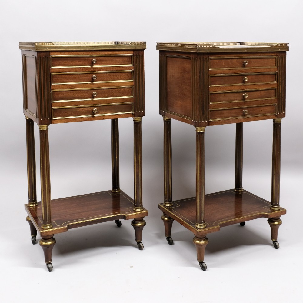 A pair of tall 19th century French Empire mahogany bedside cabinets featuring brass galleries, four drawers with brass mouldings, fluted legs, and lower shelves.