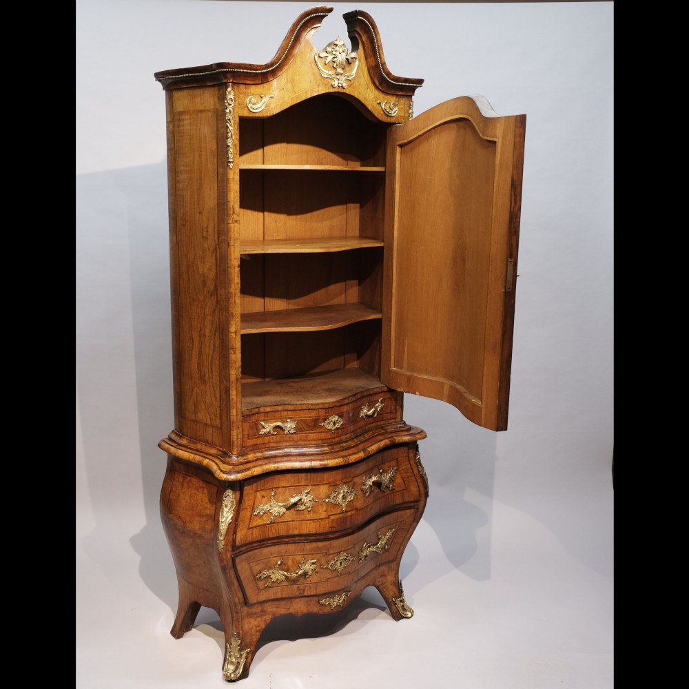 An antique 19th-century burr walnut cabinet on a bombe chest of drawers featuring ornate gilt-bronze mounts and an arched pediment top. View II
