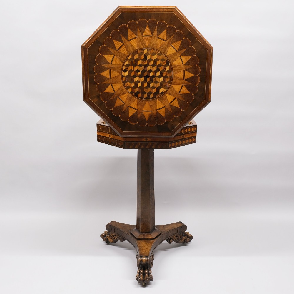 An early 19th-century octagonal work table featuring intricate geometric parquetry inlay, a faceted central column, and carved claw feet.