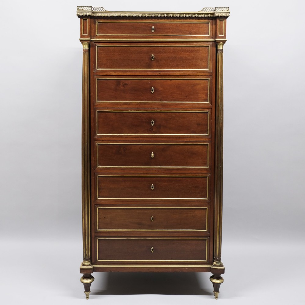 A tall mahogany semainier chest of drawers with seven brass-bordered drawer fronts, corner pilasters, and a brass gallery top. View II