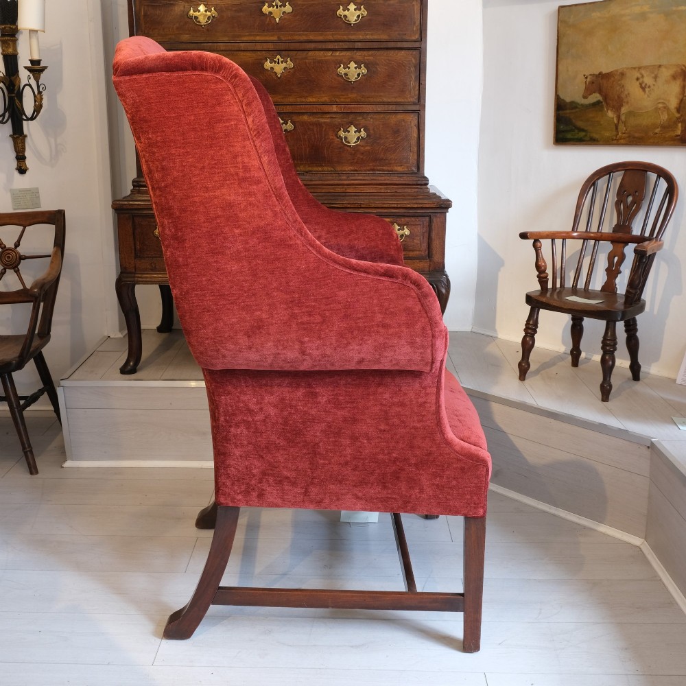 A late 19th-century wingback armchair upholstered in rich red velvet with square timber legs and a stretcher base. View II