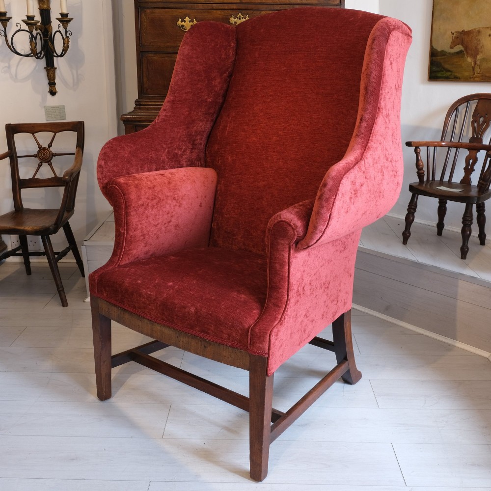 A late 19th-century wingback armchair upholstered in rich red velvet with square timber legs and a stretcher base. View III