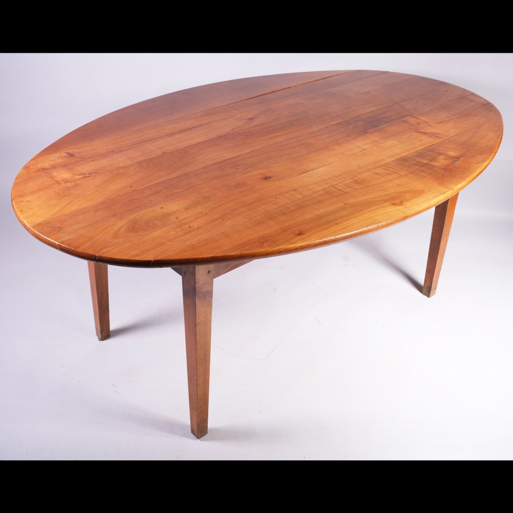 A nineteenth-century French oval dining table crafted from warm brown cherrywood with four tapered square legs. View II