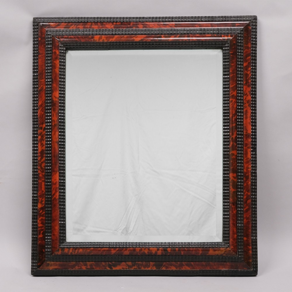 A rectangular 19th-century wall mirror featuring a frame decorated with mottled red-brown tortoiseshell veneer bordered by dark ebonised ripple mouldings.