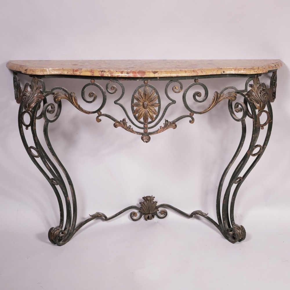 A 19th-century serpentine console table featuring a contoured marble top resting on a dark green wrought iron frame decorated with floral rosettes and scrollwork.