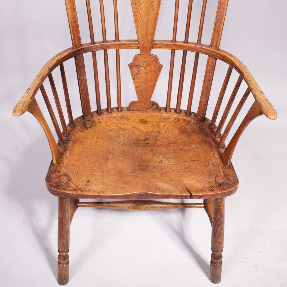 An eighteenth-century ash comb back Windsor armchair featuring a shaped crest rail, vertical spindles, a central vase splat, contoured wooden seat, and turned legs. View II
