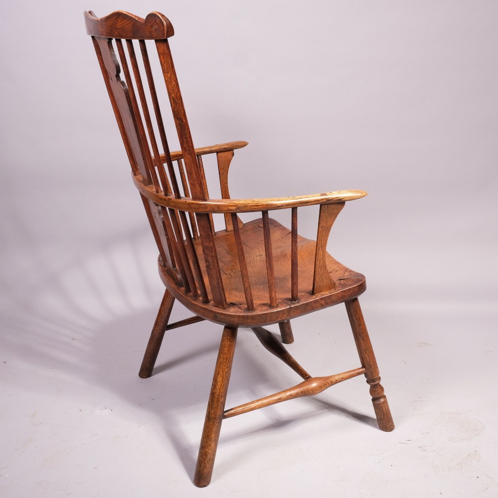 An eighteenth-century ash comb back Windsor armchair featuring a shaped crest rail, vertical spindles, a central vase splat, contoured wooden seat, and turned legs. View III