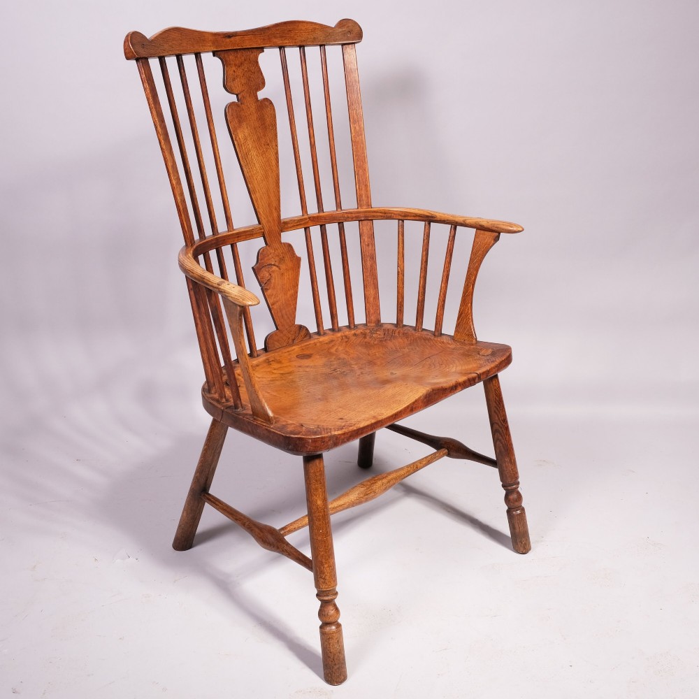 An eighteenth-century ash comb back Windsor armchair featuring a shaped crest rail, vertical spindles, a central vase splat, contoured wooden seat, and turned legs. View IV