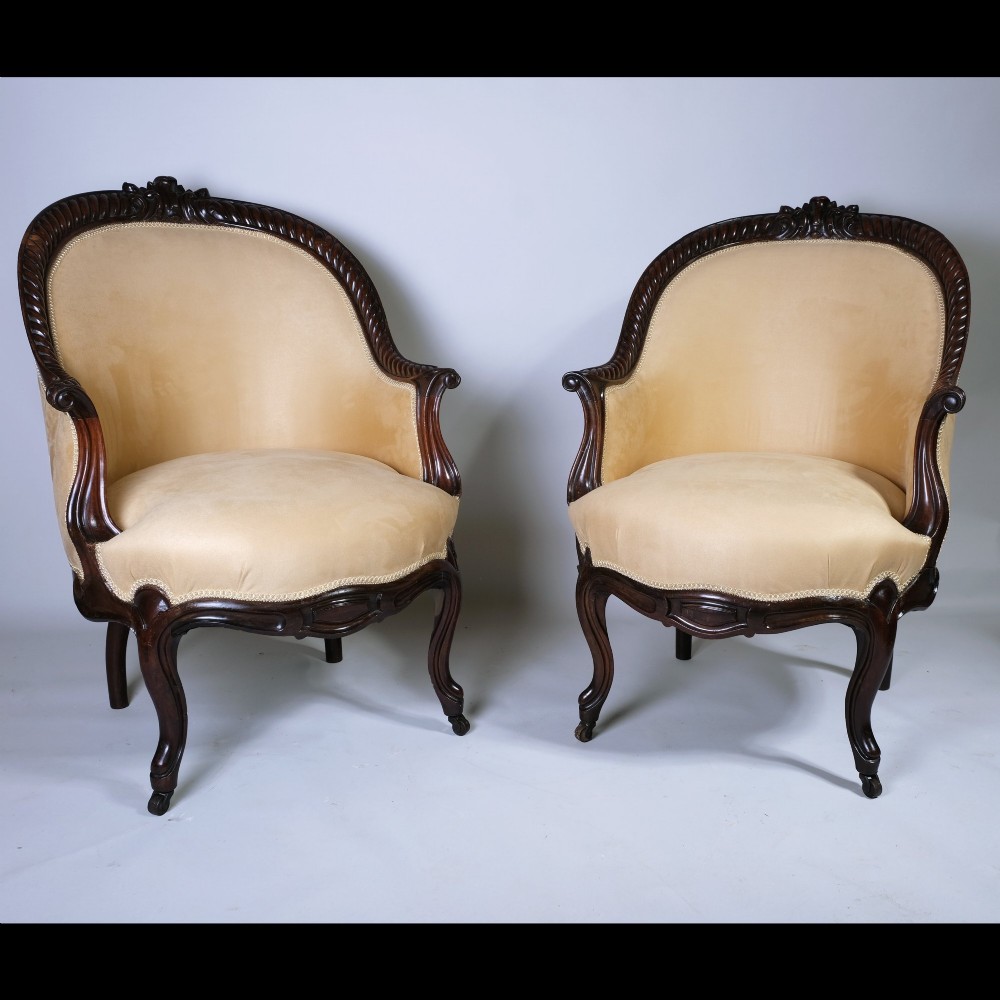 A pair of 19th-century armchairs crafted from dark Goncalo Alves wood featuring hand-carved showwood frames and cream velvet upholstery.
