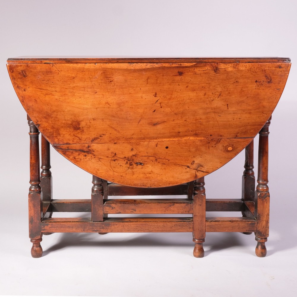 An 18th-century yew wood gateleg table featuring an oval drop-leaf top, turned legs, lower stretchers, and a single end drawer with a brass knob. View III