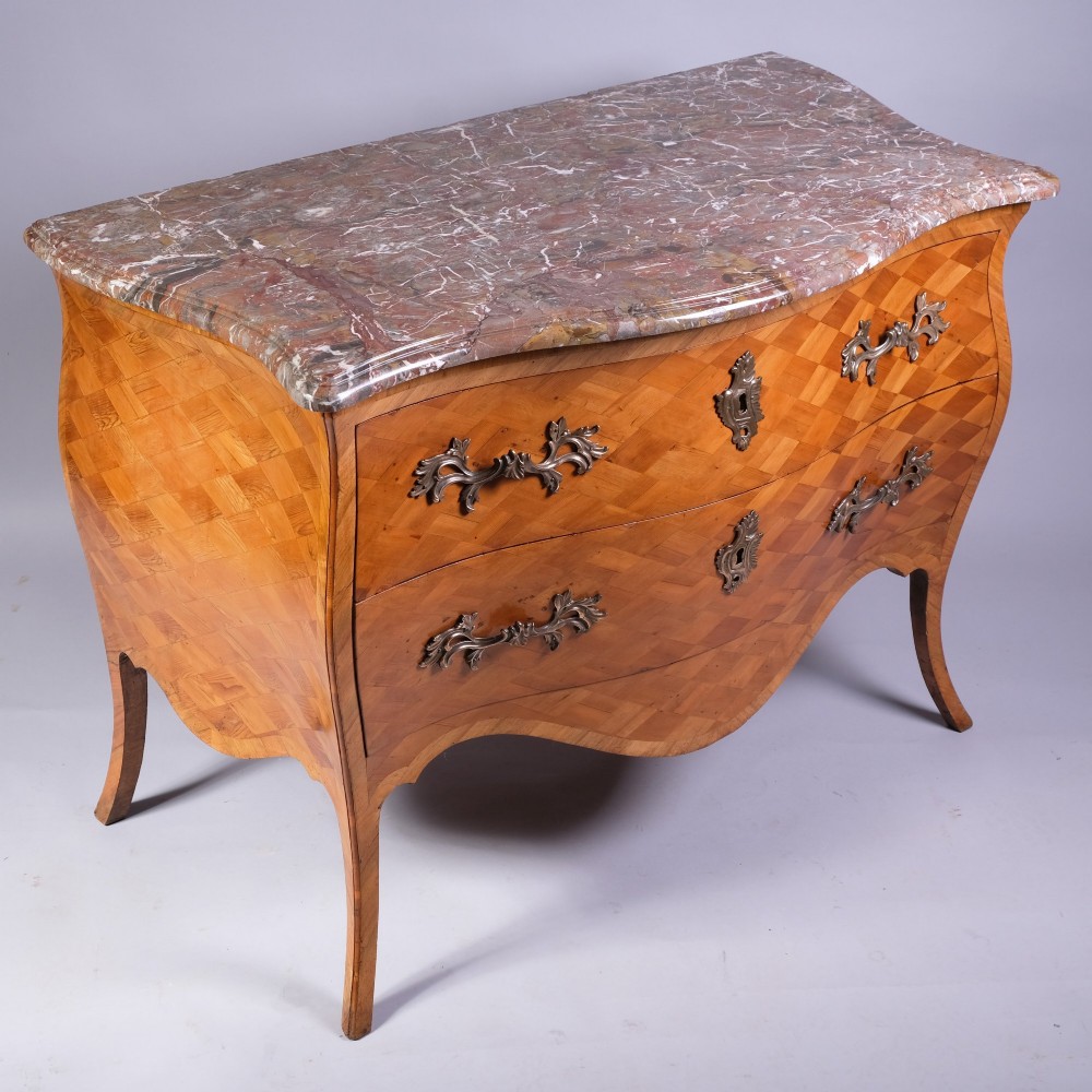 A French bombe commode featuring geometric parquetry wood veneer, two deep drawers with cast metal handles, cabriole legs, and a fitted grey veined marble top. View II