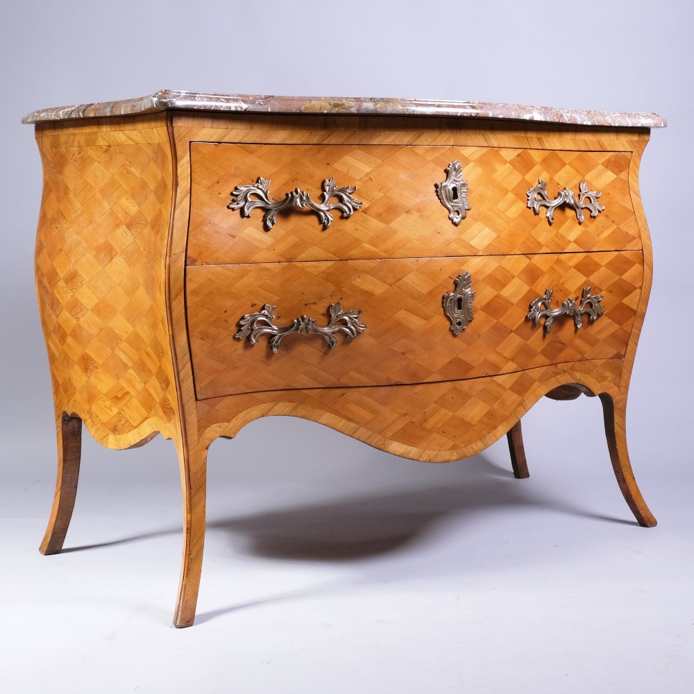 A French bombe commode featuring geometric parquetry wood veneer, two deep drawers with cast metal handles, cabriole legs, and a fitted grey veined marble top. View III