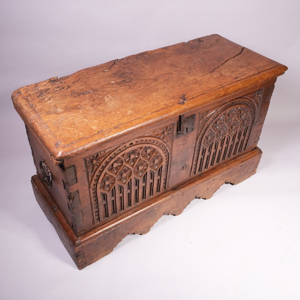 An antique oak and elm coffer featuring carved Gothic tracery arches across the front panel and a hand-forged iron lockplate. View V