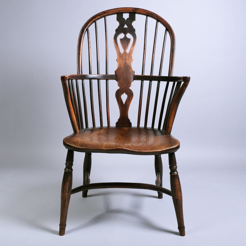 An early 19th-century Windsor armchair crafted from yew and ash wood, featuring a hoop back, pierced splat, shaped seat, and turned legs.