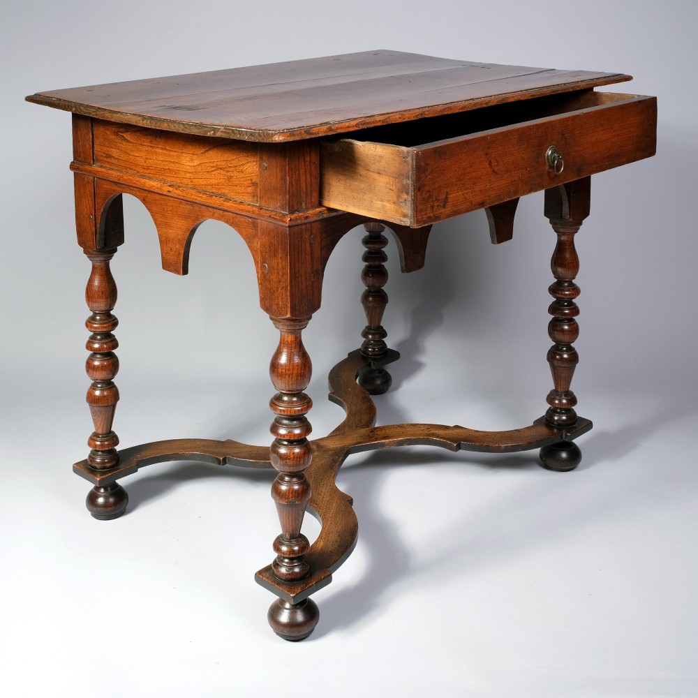 A late 17th century William and Mary period elm side table featuring turned legs, a single drawer, a shaped apron, and an X-frame stretcher. View II