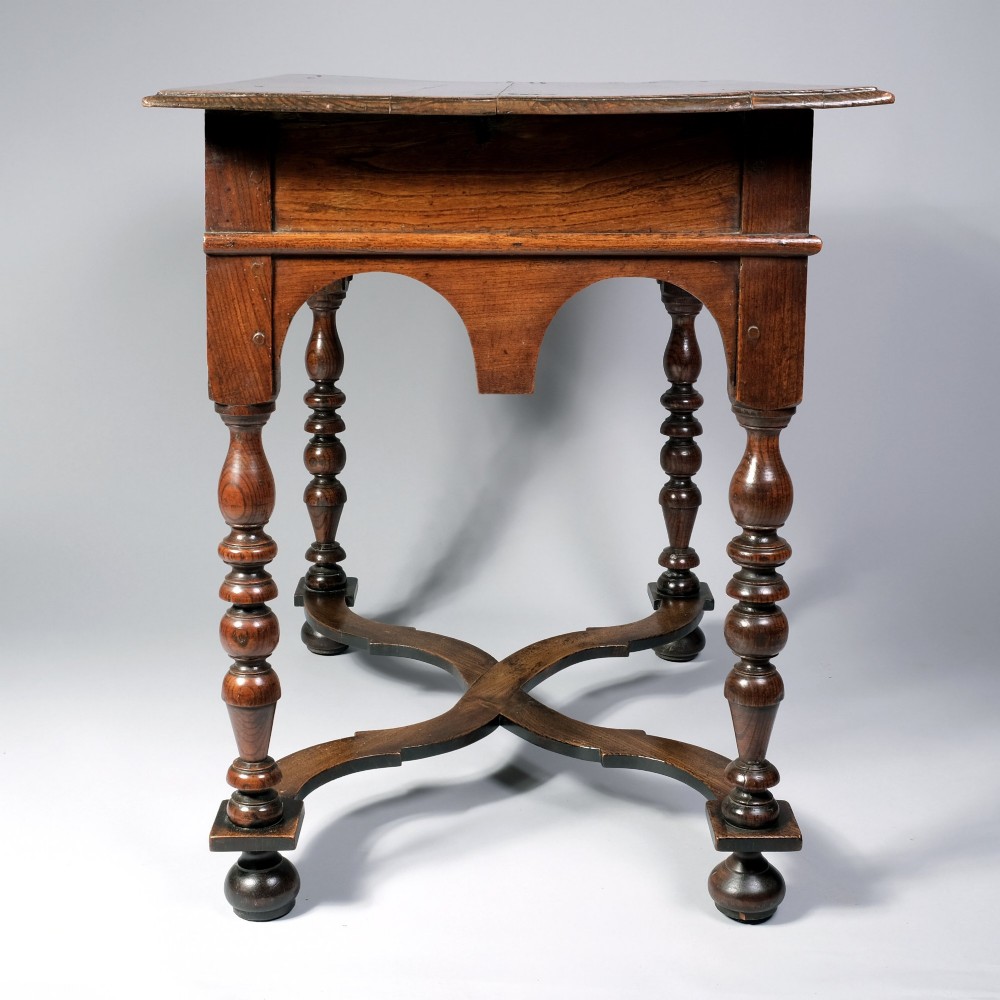 A late 17th century William and Mary period elm side table featuring turned legs, a single drawer, a shaped apron, and an X-frame stretcher. View III