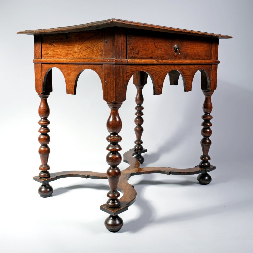 A late 17th century William and Mary period elm side table featuring turned legs, a single drawer, a shaped apron, and an X-frame stretcher. View IV