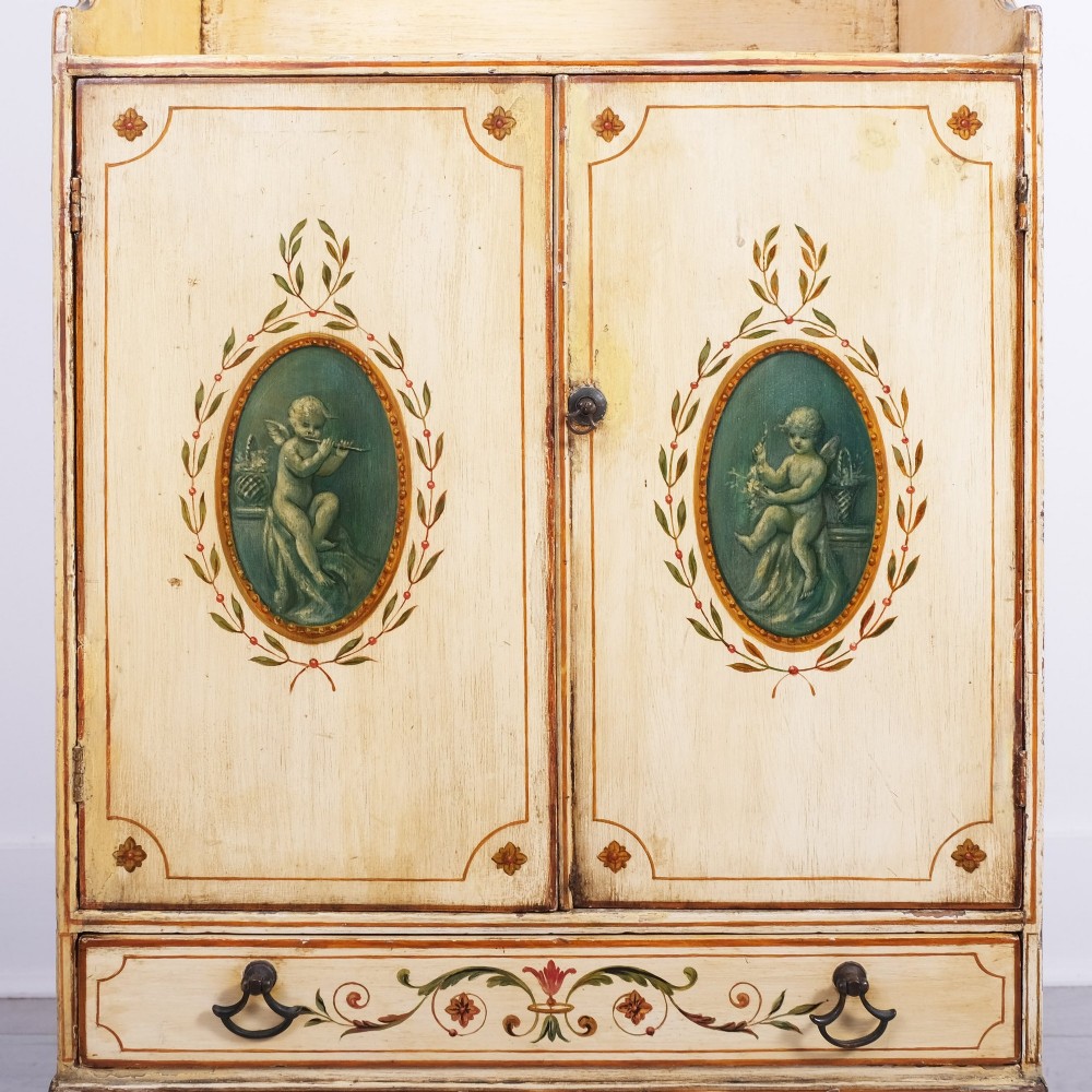 A late 18th-century George III painted waterfall bookcase featuring tiered open shelves above a two-door cabinet with green painted medallions and a single drawer on tapered legs. View II