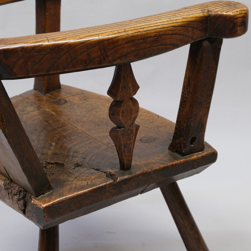 An antique mid-18th century dark oak panel-backed Windsor armchair featuring curved armrests, a shaped cresting rail, and splayed turned legs. View II