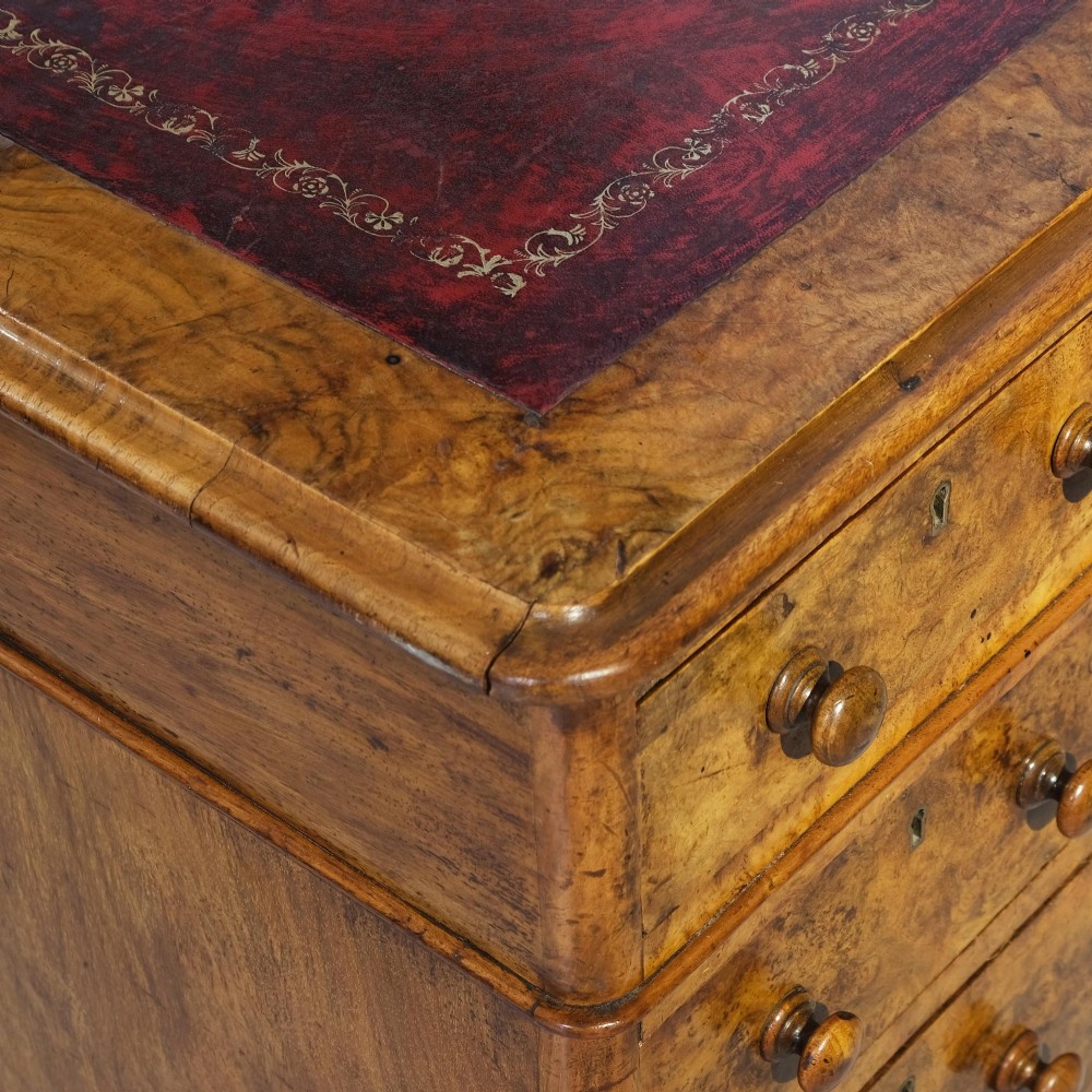 A Victorian burr walnut pedestal desk featuring nine drawers with turned wooden knobs and an inset leather writing surface. View III
