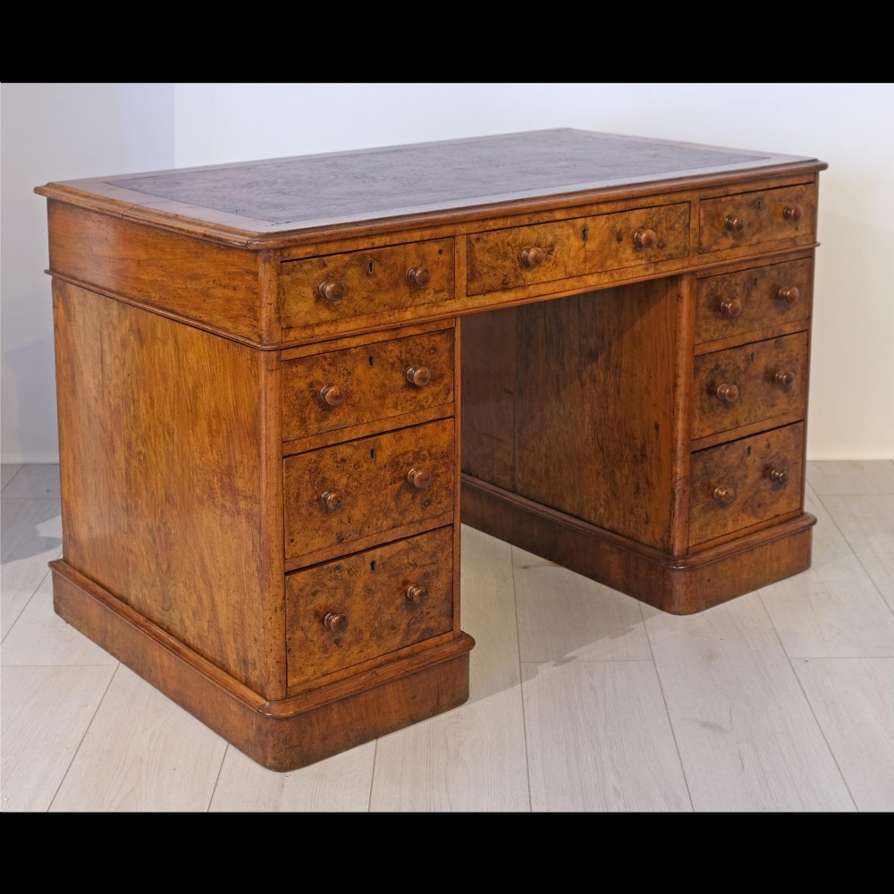 A Victorian burr walnut pedestal desk featuring nine drawers with turned wooden knobs and an inset leather writing surface. View IV