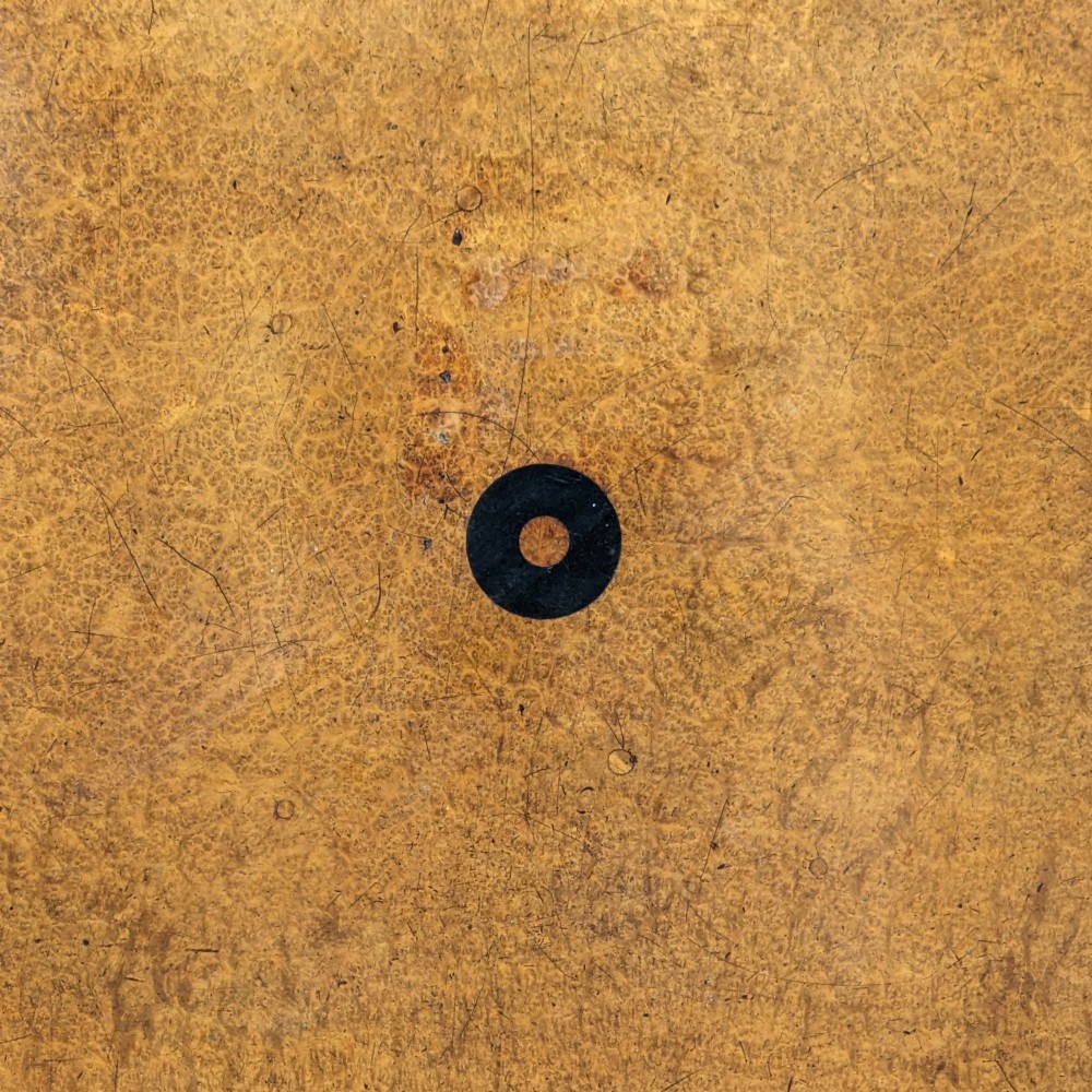 A Regency period oval tilt-top table crafted from amboyna wood with an ebony inlaid border, supported by a central pedestal and tripod legs with brass lion paw castors. View III