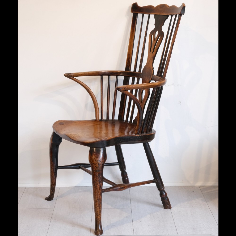 An 18th-century comb back Windsor armchair in warm brown timber, featuring a pierced central splat, spindle back, cabriole front legs, and a carved saddle seat. View II