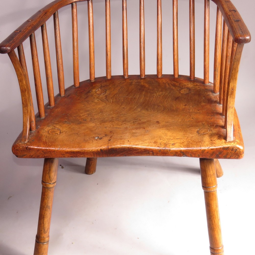 A pair of late eighteenth-century timber comb-back Windsor armchairs featuring pierced splats, slender spindles, saddled seats, and splayed turned legs. View III