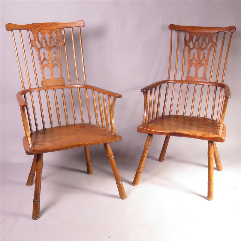 A pair of late eighteenth-century timber comb-back Windsor armchairs featuring pierced splats, slender spindles, saddled seats, and splayed turned legs. View IV