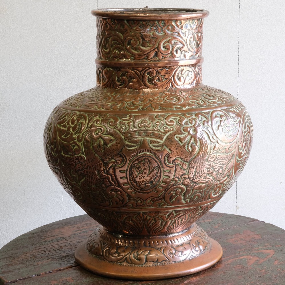 A large 18th-century copper jug featuring hand-chased foliate scrollwork and animal motifs, complete with a domed chained lid and curved handle. View III