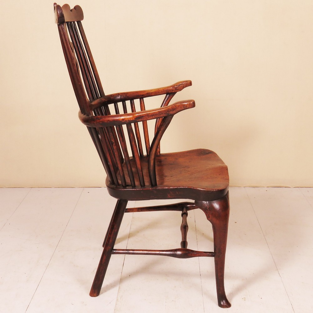 An 18th-century comb-back Windsor armchair in dark finished wood, featuring a pierced central splat, vertical spindles, curved armrests, and cabriole front legs. View II