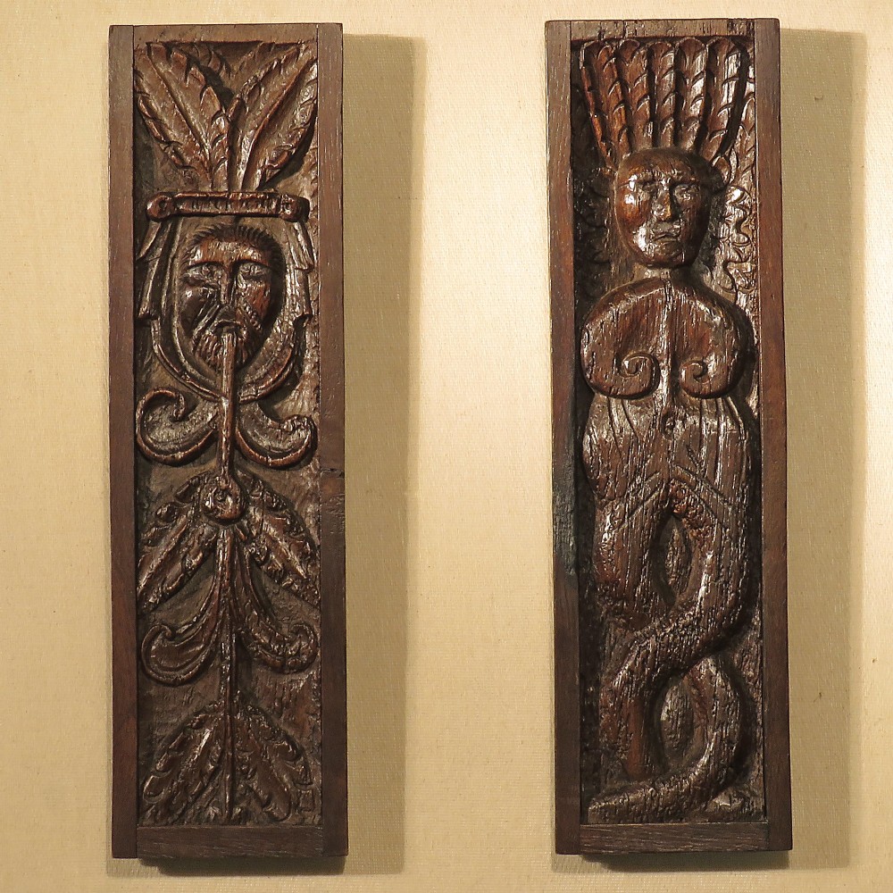 Pair of vertical dark oak relief carved panels depicting a Green Man with foliage and a stylised mythical figure.