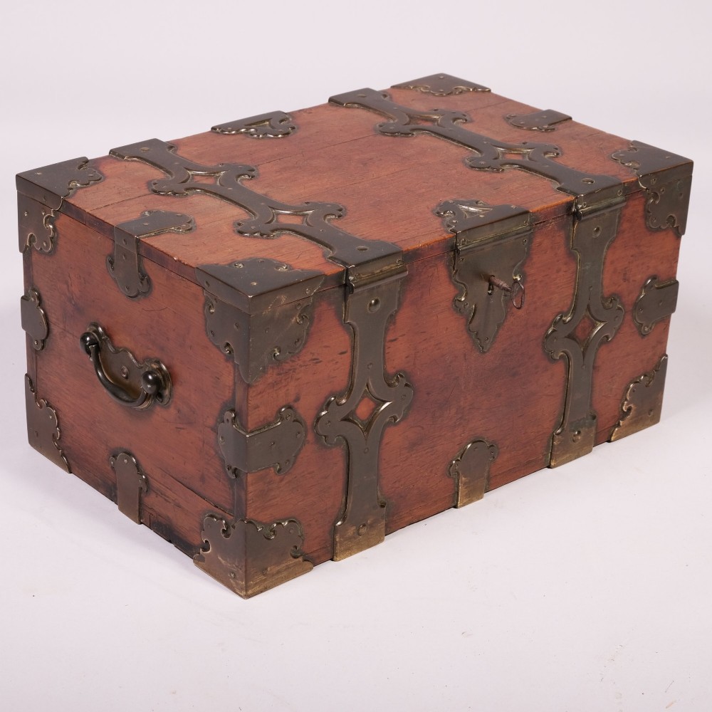 An early eighteenth-century rectangular camphor wood casket featuring ornate cut-out brass strapwork, corner brackets, and side handles.
