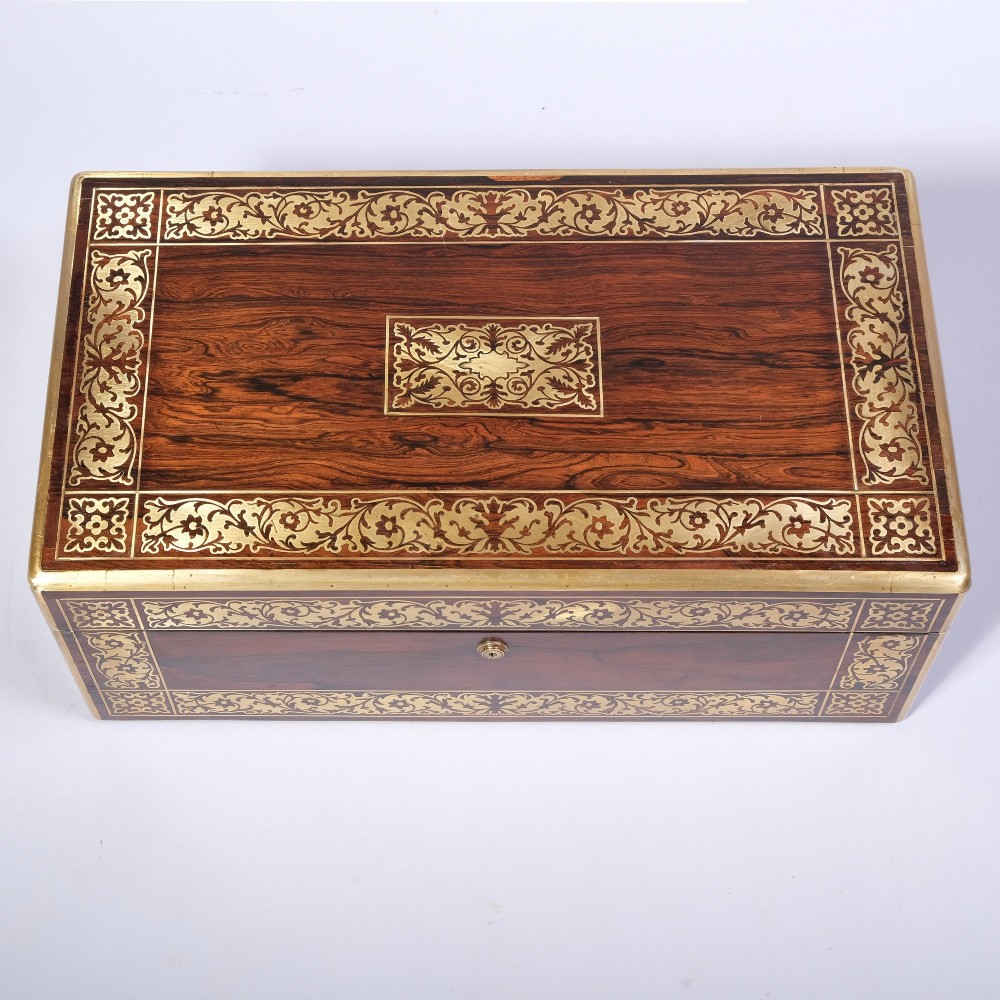 A rectangular dark wood writing box featuring intricate floral brass scrollwork inlay across the top lid and front panel.
