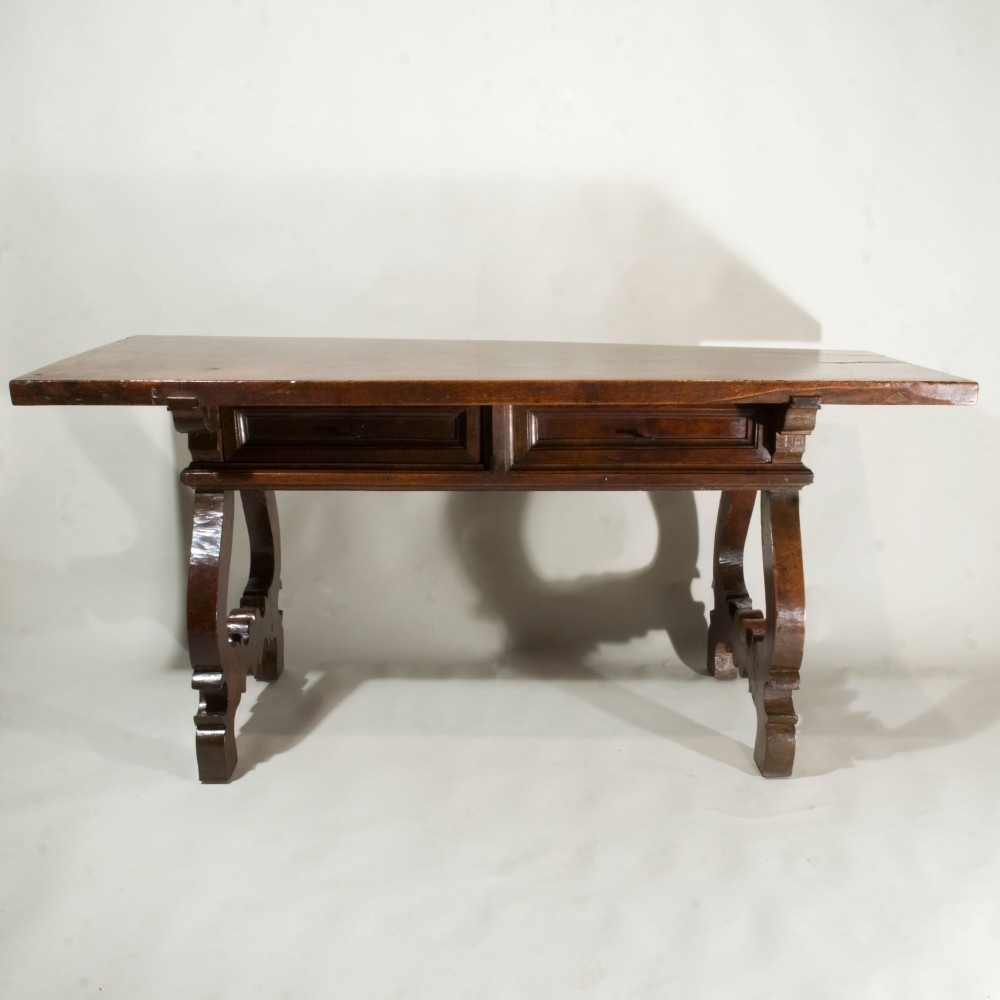 A 17th-century Spanish walnut table featuring curved lyre legs, decorative carved stretchers, and frieze drawers. View II
