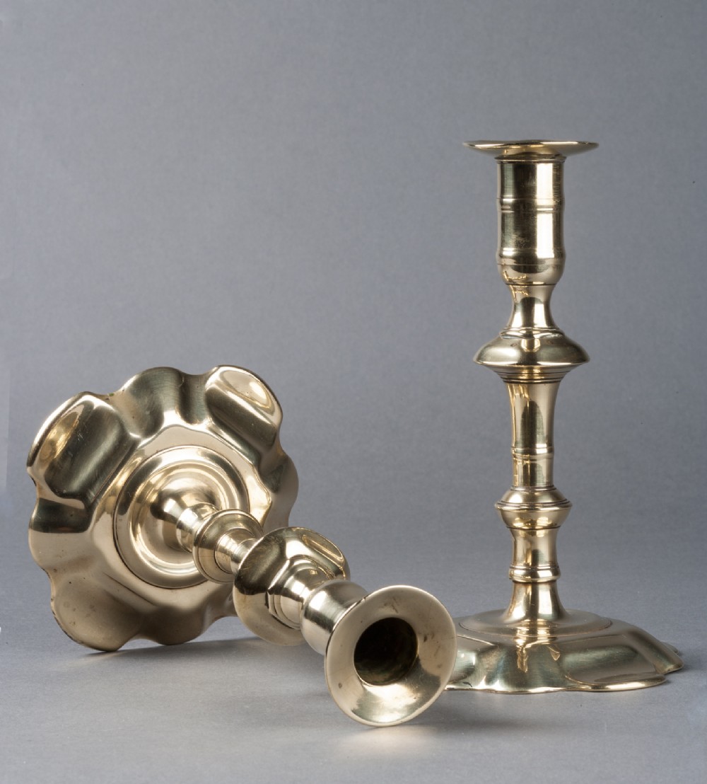 A pair of mid-18th century cast brass candlesticks featuring turned stems and six-lobed petal bases.