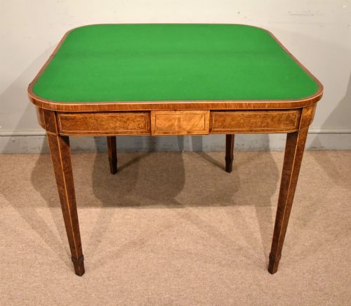 fig 1. A George III fold-over card table with burr yew wood veneer, an oval central inlay, and square tapered legs.