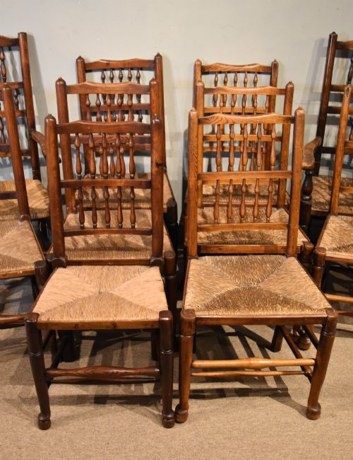 fig 1. A set of ten brown oak dining chairs featuring double-tier spindle backs, woven rush seats, and turned stretchers.