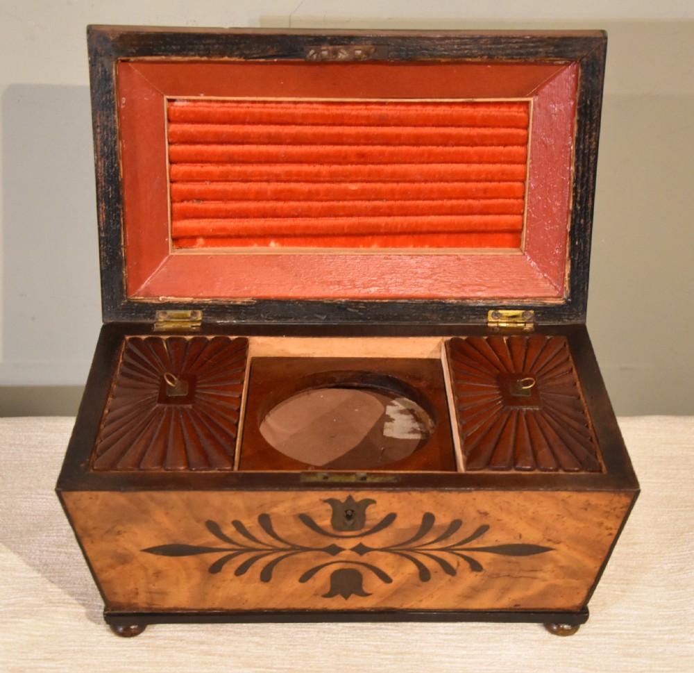 A 19th-century sarcophagus-shaped mahogany tea caddy with a carved fluted lid, ebony floral inlay on the front, and small feet. View V