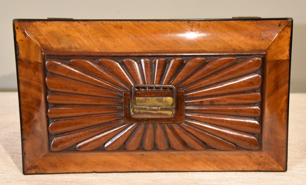 A 19th-century sarcophagus-shaped mahogany tea caddy with a carved fluted lid, ebony floral inlay on the front, and small feet. View VIII