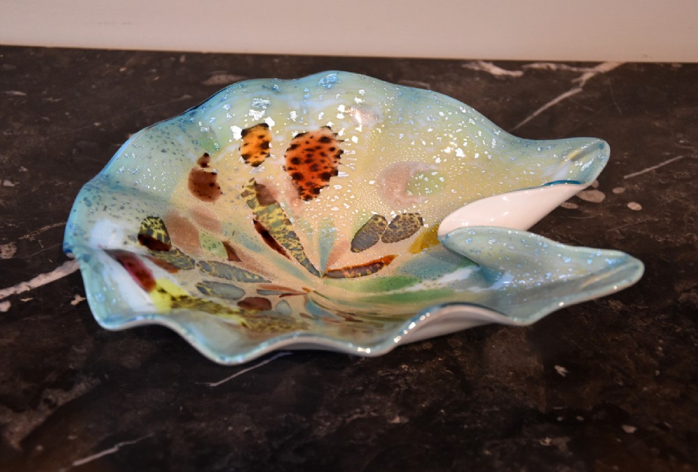 An asymmetrical vintage Murano glass bowl featuring speckled multi-coloured patterns and metallic aventurine inclusions on a dark surface.