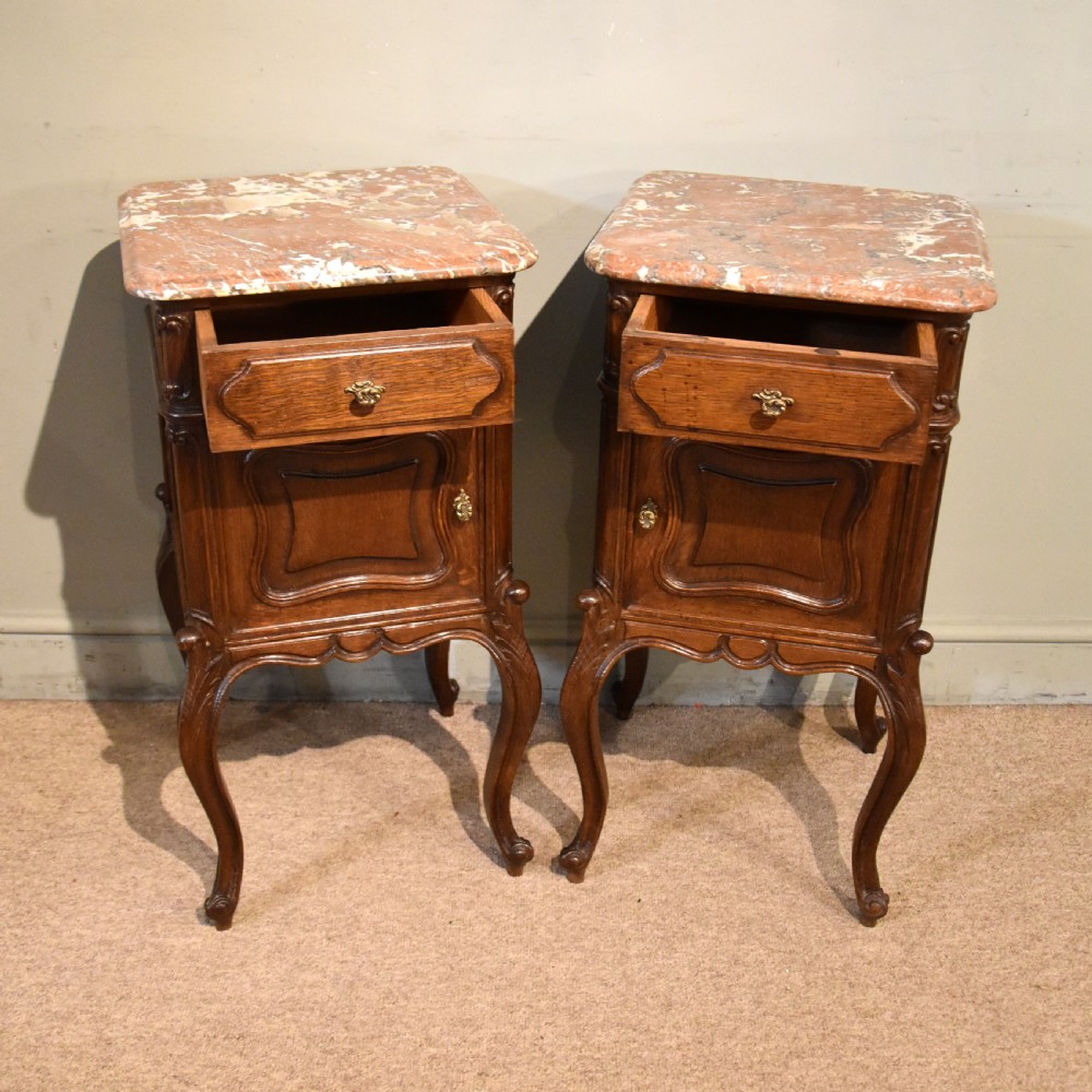 A pair of French carved oak bedside cabinets with variegated pink marble tops, single drawers, framed cupboard doors, and slender cabriole legs. View III