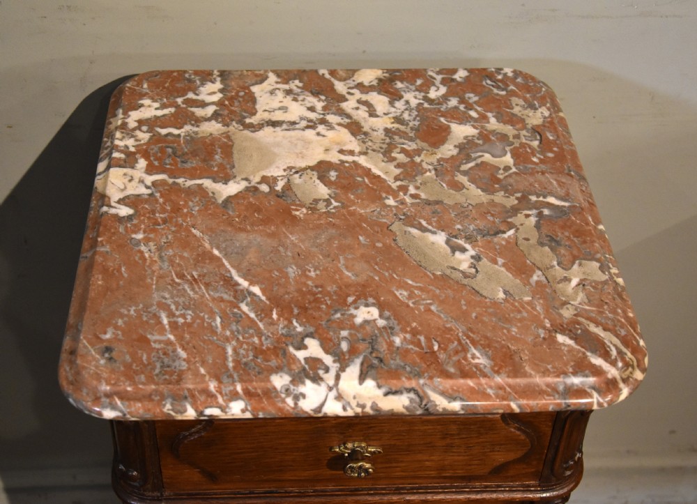 A pair of French carved oak bedside cabinets with variegated pink marble tops, single drawers, framed cupboard doors, and slender cabriole legs. View VII