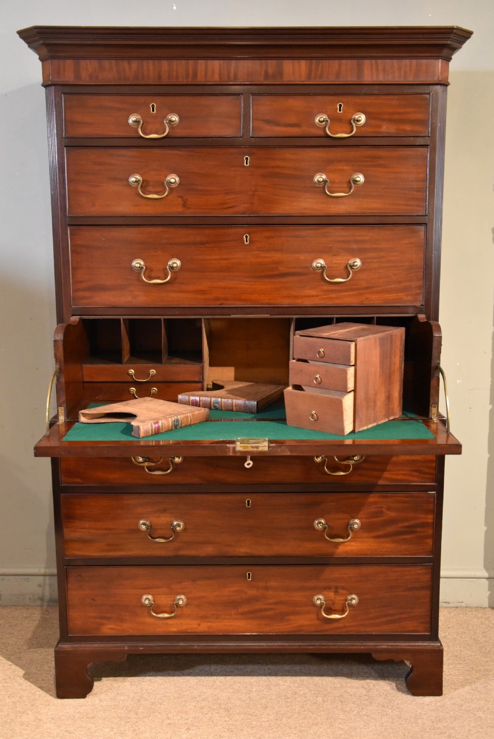 A George III mahogany chest on chest with an open secretaire drawer displaying small internal drawers, pigeonholes, and a green writing surface.