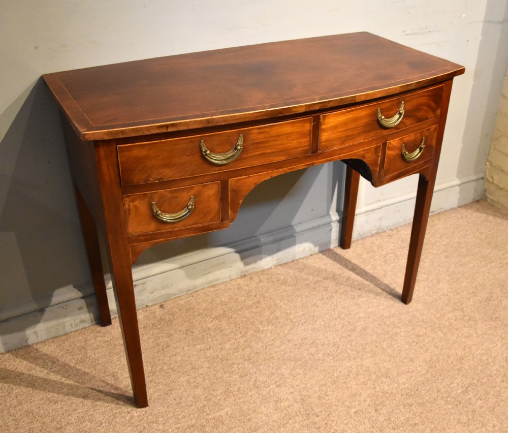A 19th-century mahogany side table featuring four drawers with curved brass drop handles and an arched central apron set on four square tapering legs. View III